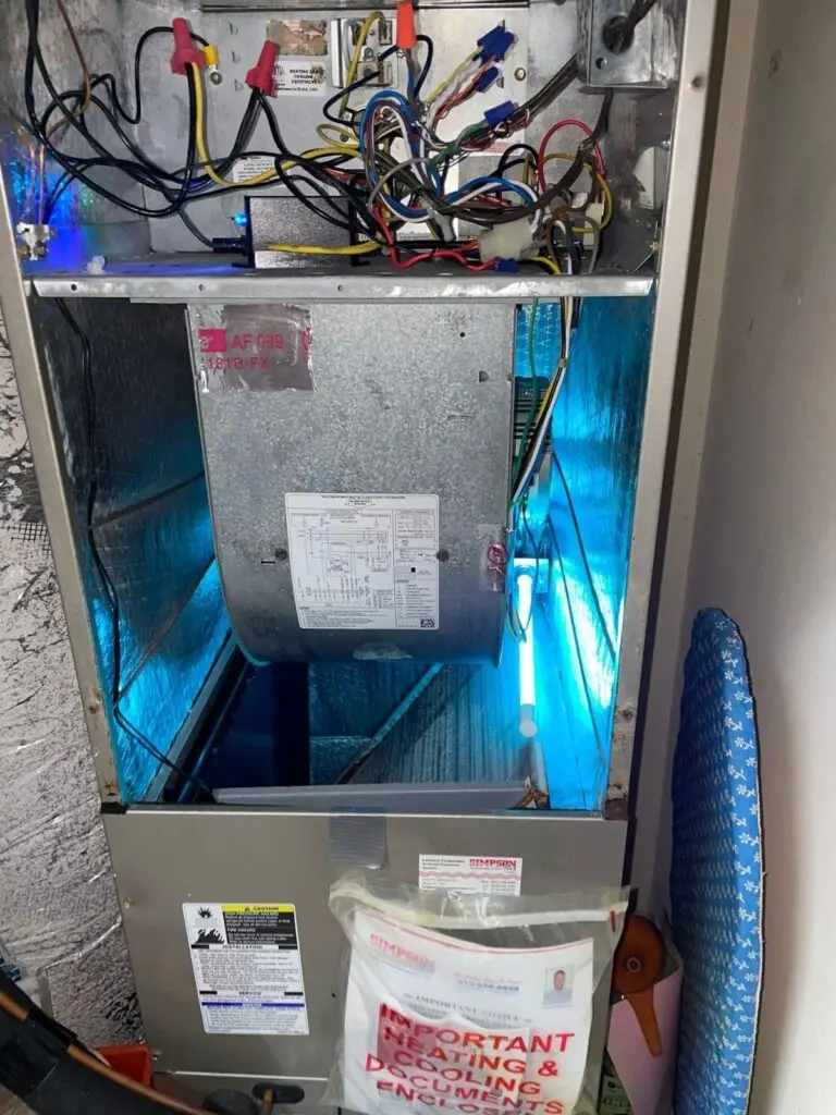 Internal view of an HVAC air handler cabinet featuring an active blue UV germicidal light and complex control wiring.