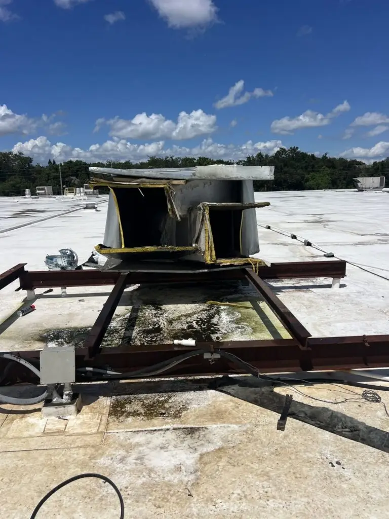 An empty HVAC rooftop curb adapter on a white roof showing the internal duct openings.