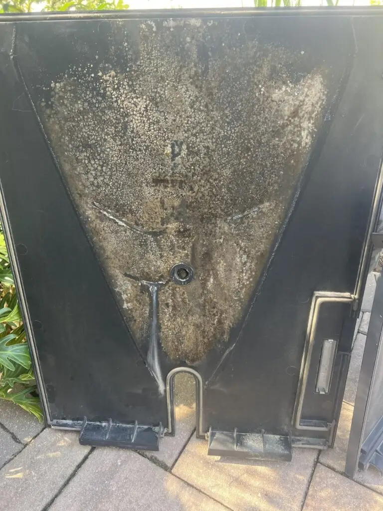HVAC drain pan before cleaning, with visible mold growth covering the surface.
