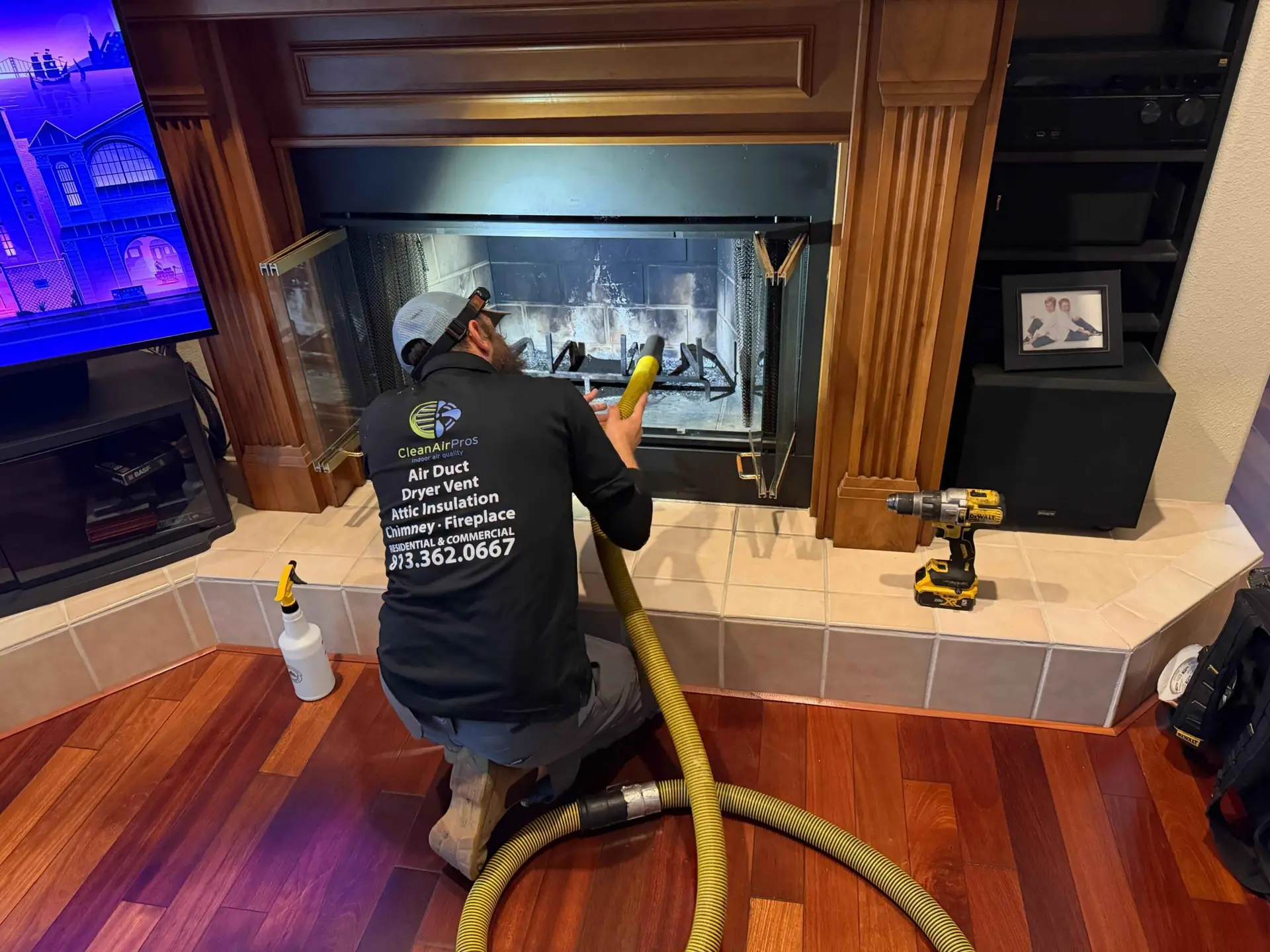 Technician cleaning residential fireplace using professional chimney vacuum system.