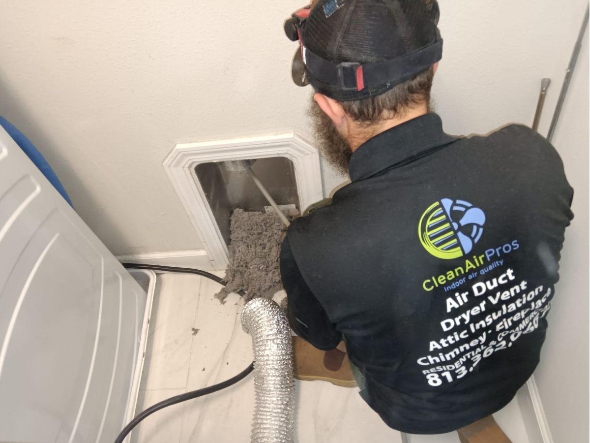 Technician cleaning a dryer vent in a residential home, removing lint buildup to improve safety and airflow, showcasing professional dryer vent cleaning services by CleanAirPros.