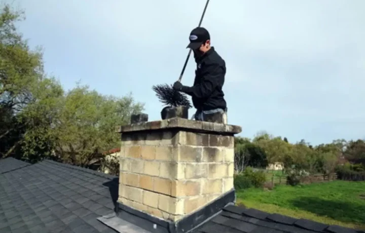 Chimney cleaning service: Professional technician sweeping chimney to ensure safe and efficient operation.