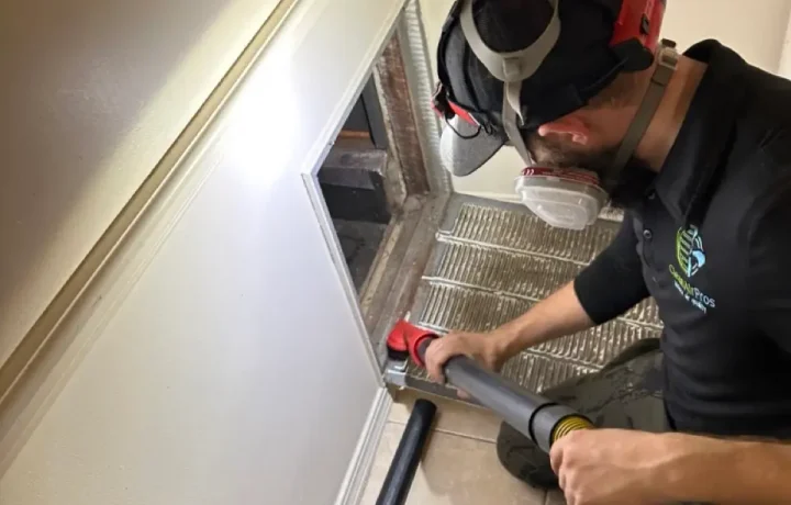 Professional cleaning debris from floor air vent using duct cleaning vacuum.