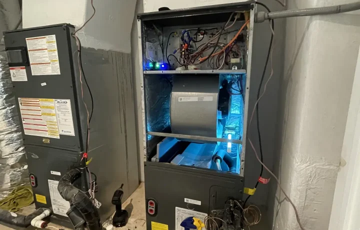 "HVAC system with open panel showing internal components and tools used for maintenance, indicating ongoing repair or service work.