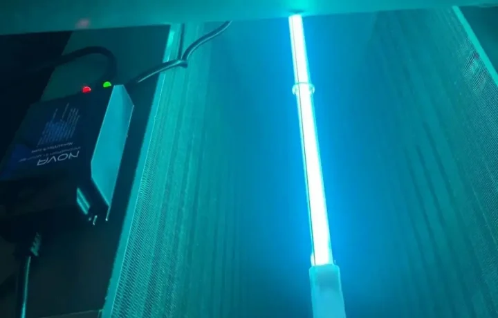 Bright blue UV light bar illuminating the metal fins of an HVAC evaporator coil to prevent mold growth.