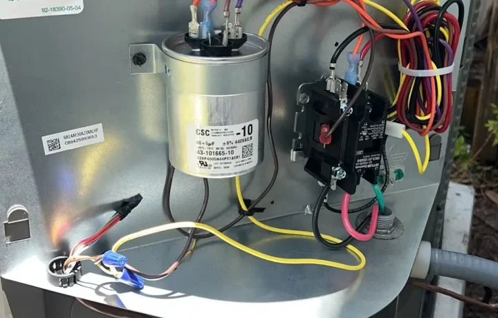 New silver run capacitor and black contactor professionally wired inside an HVAC service panel.
