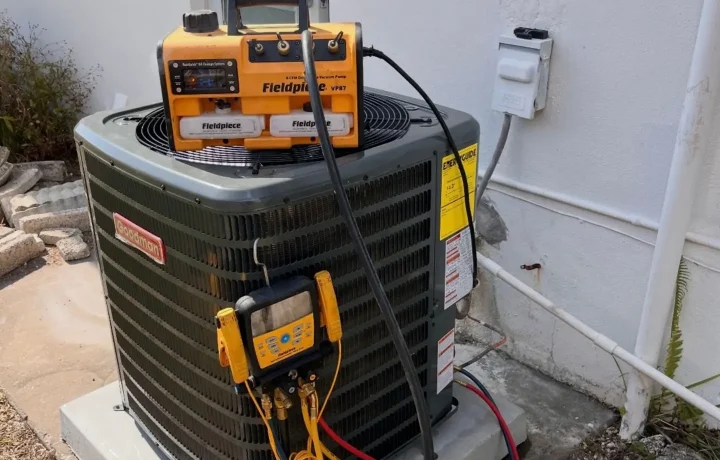 HVAC technician performing system charging with gauges attached to refrigerant lines during repair work.