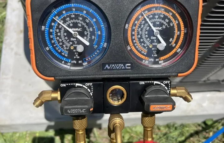 Digital NAVAC manifold gauges displaying high-precision pressure and temperature readings for an HVAC system.