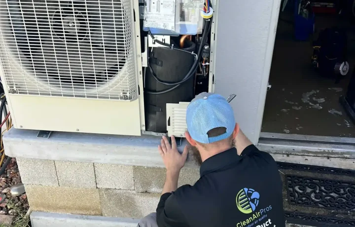 HVAC technician servicing the outdoor unit, showing internal components and performing maintenance for efficient system operation.