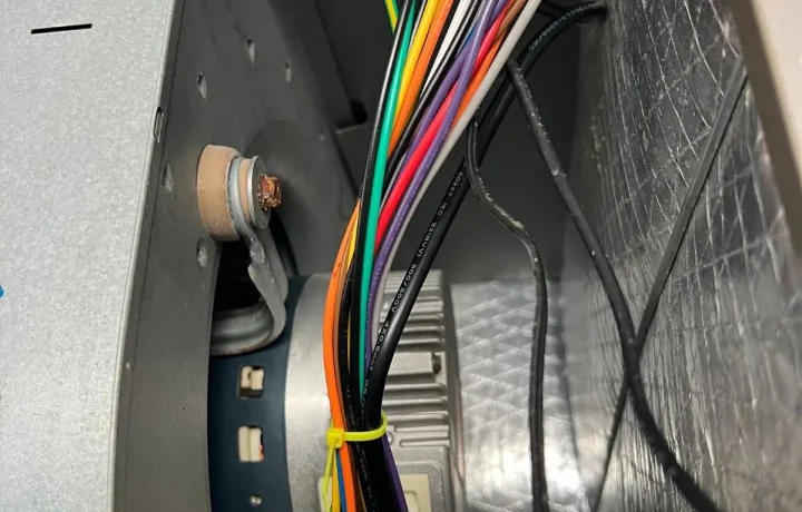 Close-up of an HVAC blower motor and internal wiring harness during a professional inspection. Demonstrating precision electrical work and component maintenance for indoor air quality systems.
