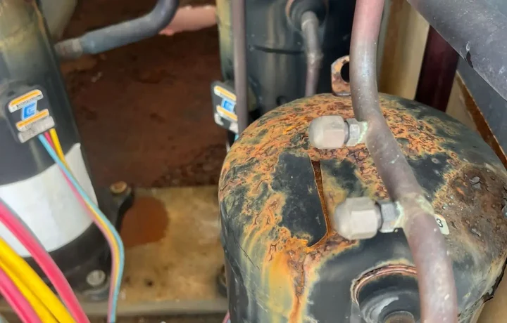 Close-up of a rusty HVAC compressor showing wear and tear, indicating the need for maintenance or repair.